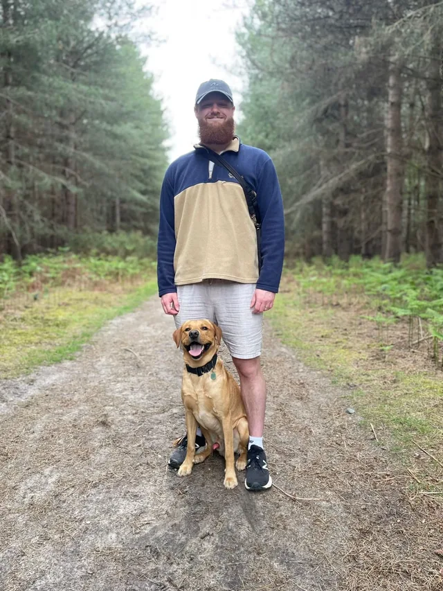 Danny, founder of Elsom Canine, with his fox red Labrador on a woodland trail